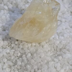 Citrino natural en bruto sobre sal gruesa blanca, piedra asociada tradicionalmente a la abundancia y la prosperidad.
